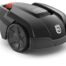 Husqvarna Automower 105 robotic lawn mower cutting grass in a small garden with flower beds and trees.