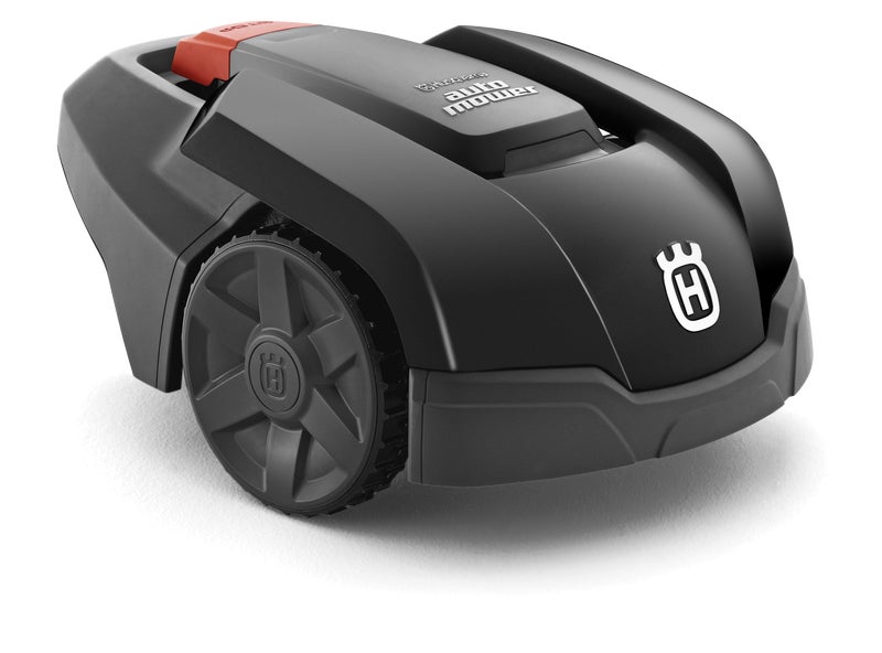 Husqvarna Automower 105 robotic lawn mower cutting grass in a small garden with flower beds and trees.