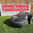 Husqvarna Automower® 430X NERA robotic lawn mower operating on a large, uneven lawn. The mower is shown navigating rugged terrain near garden plants, demonstrating its robust design, obstacle detection sensors, and wire-free satellite installation capability. Ideal for lawns up to 3200 m².