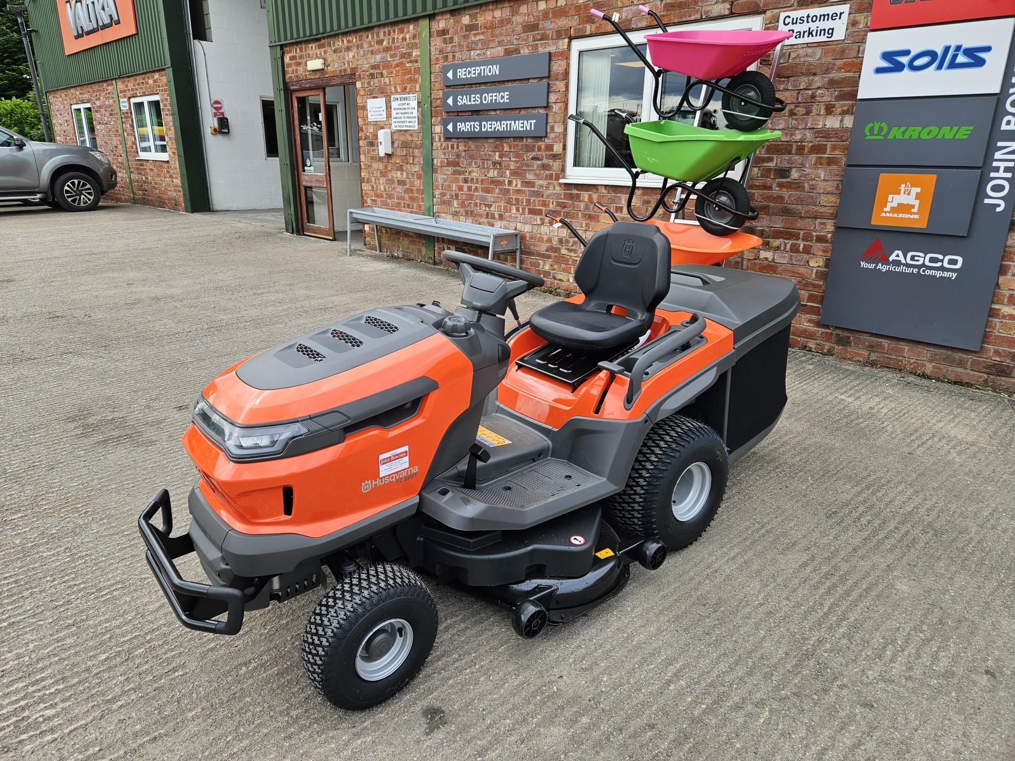 Husqvarna TC220T riding lawn mower with a sleek orange and gray body, high-back seat, and wide cutting deck, designed for residential lawn care with superior traction and comfort.