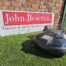 Husqvarna Automower® 450X NERA robotic lawn mower working on a large, sloped lawn with dense grass and landscaping. The mower is shown navigating rough terrain, highlighting its durable design, obstacle detection sensors, and satellite-guided wire-free installation—ideal for lawns up to 5000 m²