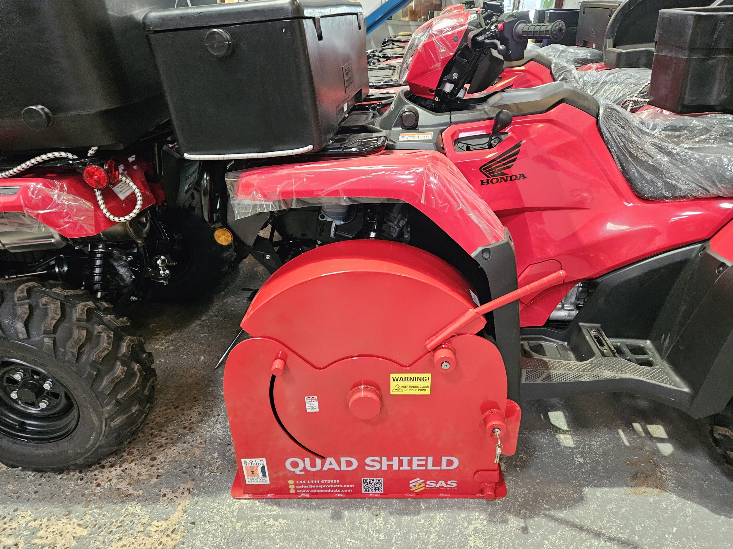 SAS Quad Shield Wheel Clamp securely locking an ATV wheel, showing heavy-duty ground bolts and steel-encased anti-theft locking mechanism.