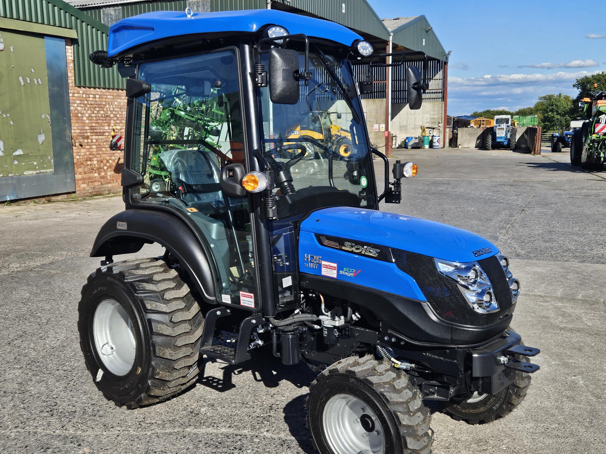 Brand new Solis 26HST compact tractor with cab, shown on our yard with all-weather enclosed cabin and industrial tyres.
